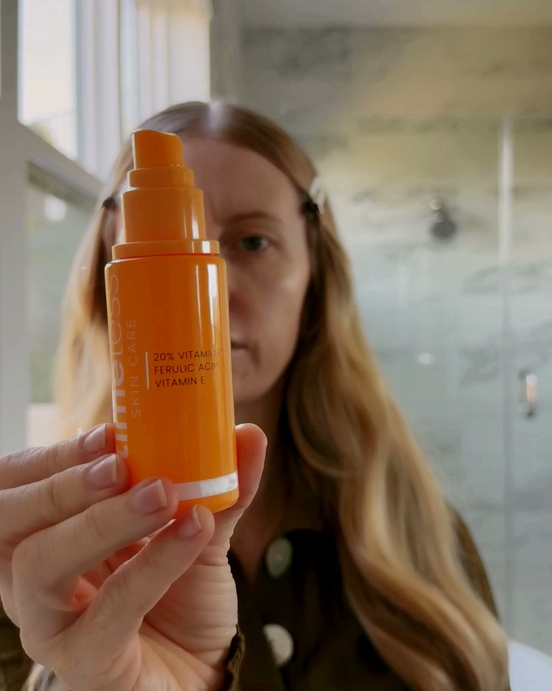Laura holding Timeless 20% Vitamin C serum in window light